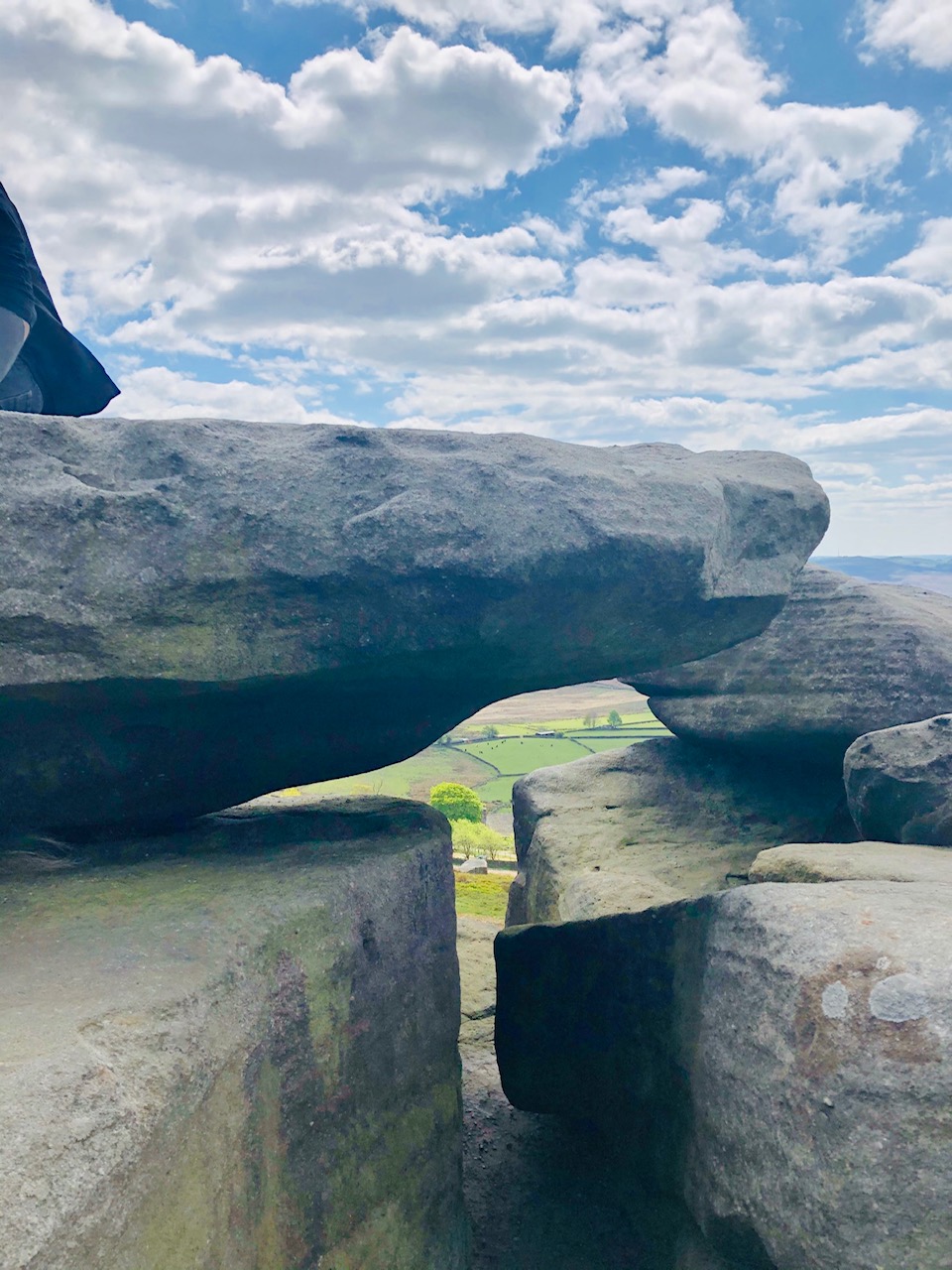 Close-up of a natural rock formation at Stanage Edge, featuring a keyhole opening framing the rolling Derbyshire countryside beyond